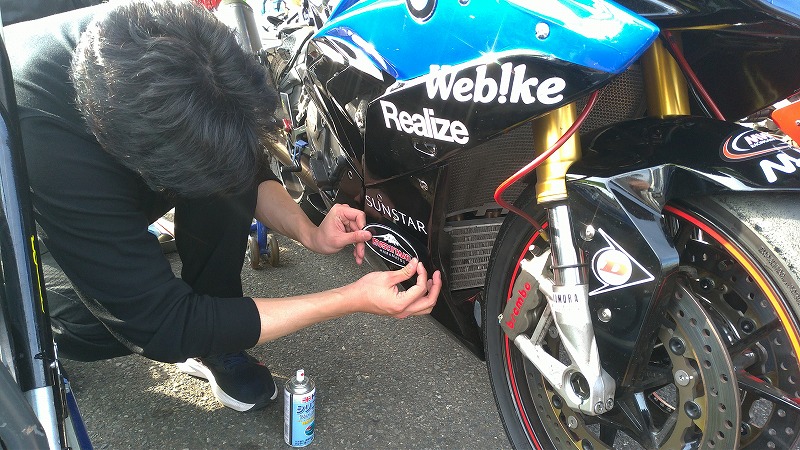 筑波ロードレース選手権 TC-Formula/ST1000 参加車両のカウルにスポンサーステッカーを貼っていただく様子